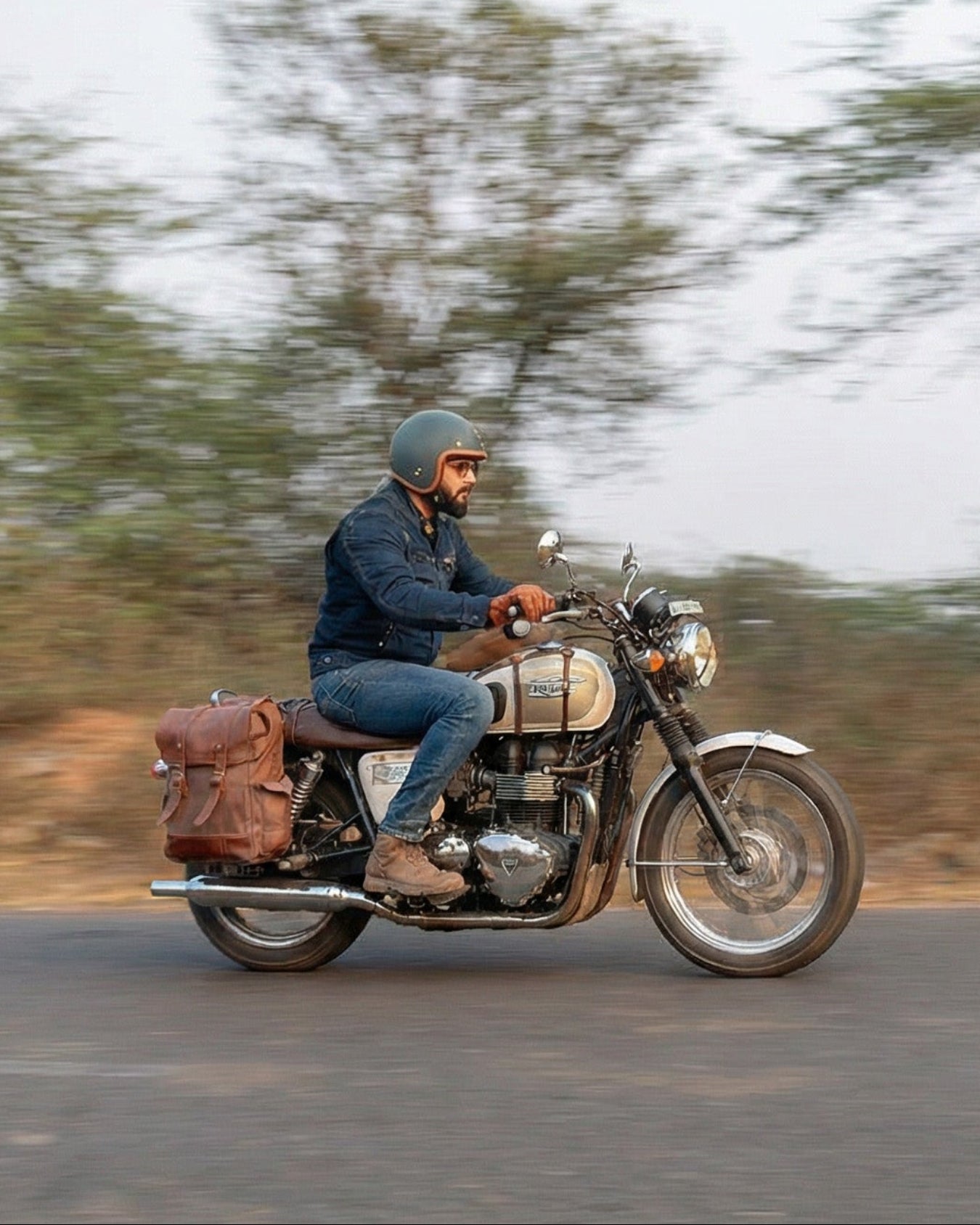 Person riding a motorcycle on a road with trees in the background