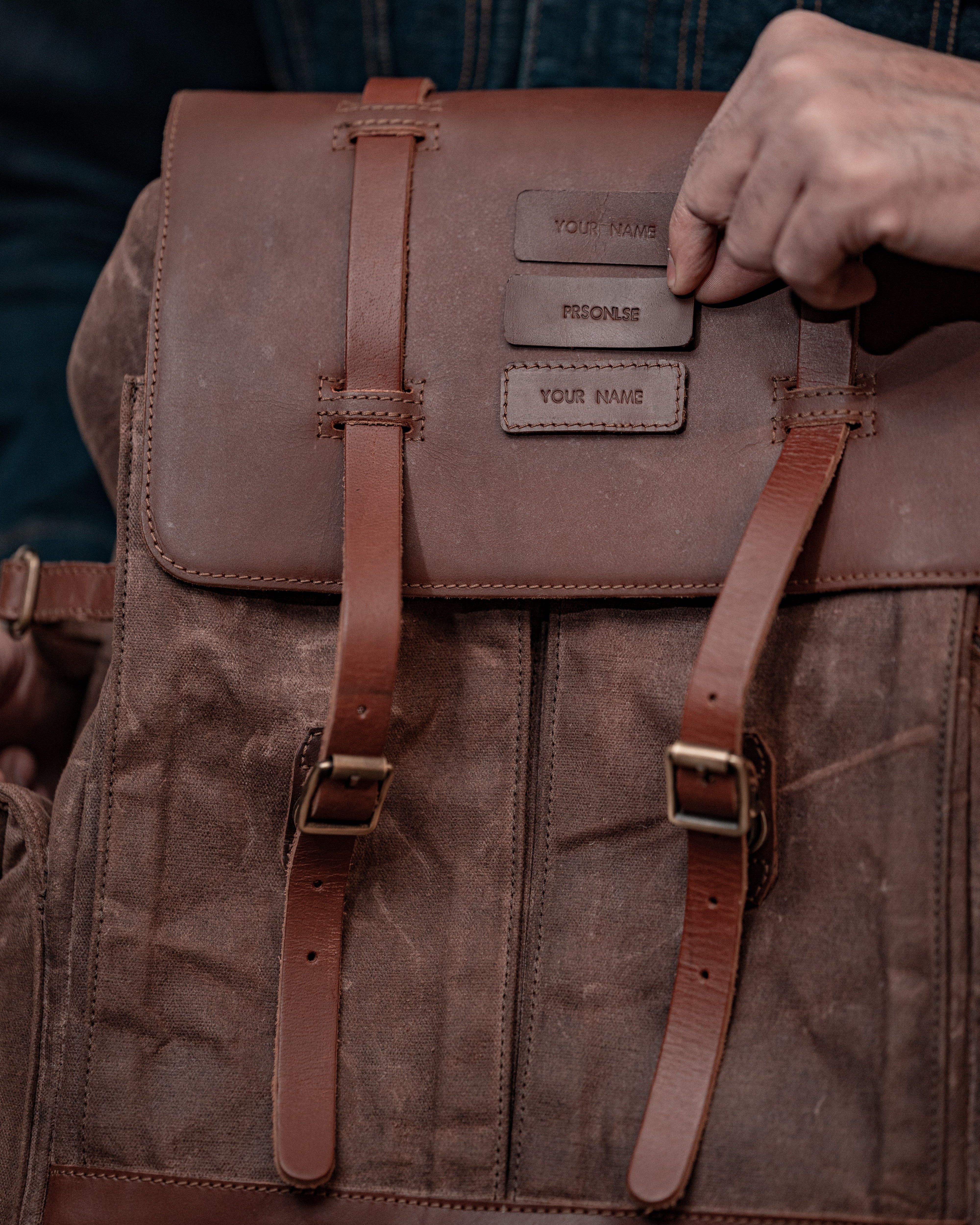 Brown leather backpack with straps being adjusted, close-up view.