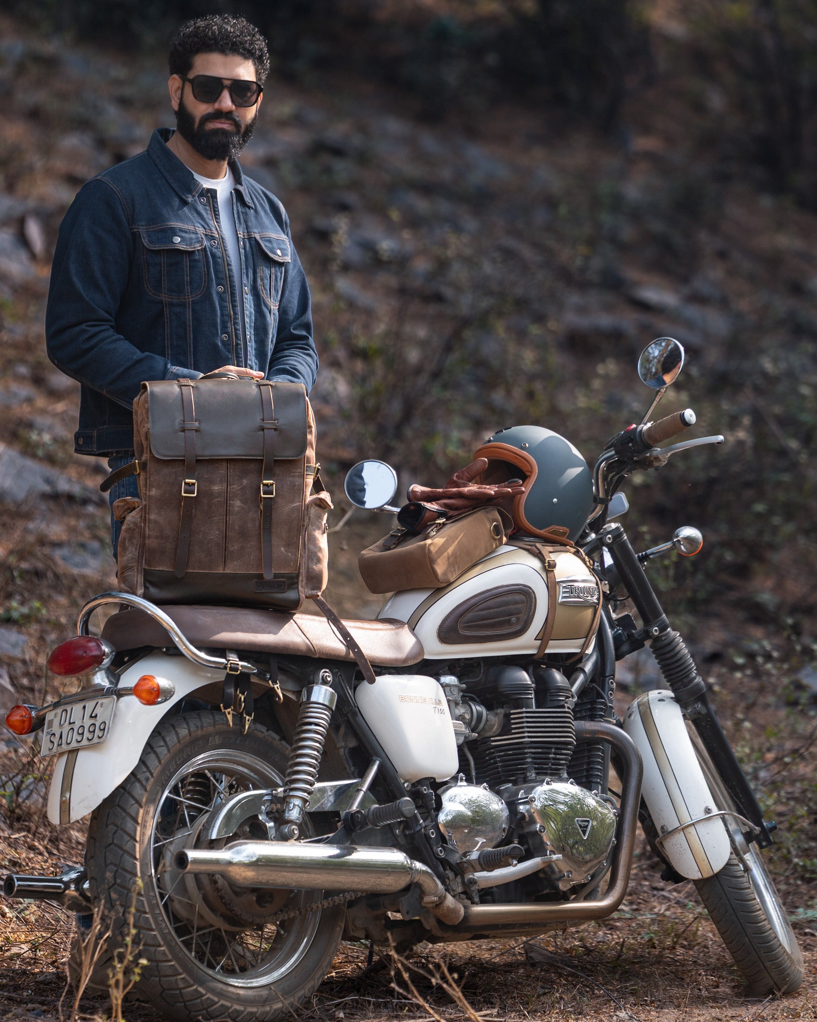 Man standing next to a motorcycle with a saddlebag in a natural setting