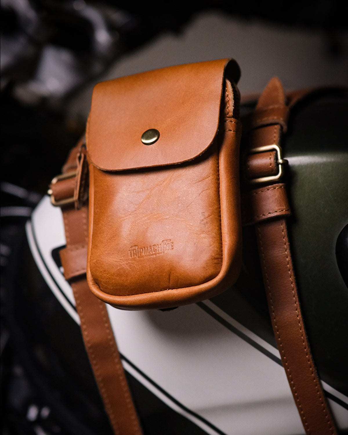 Brown leather pouch attached to a motorcycle fuel tank strap