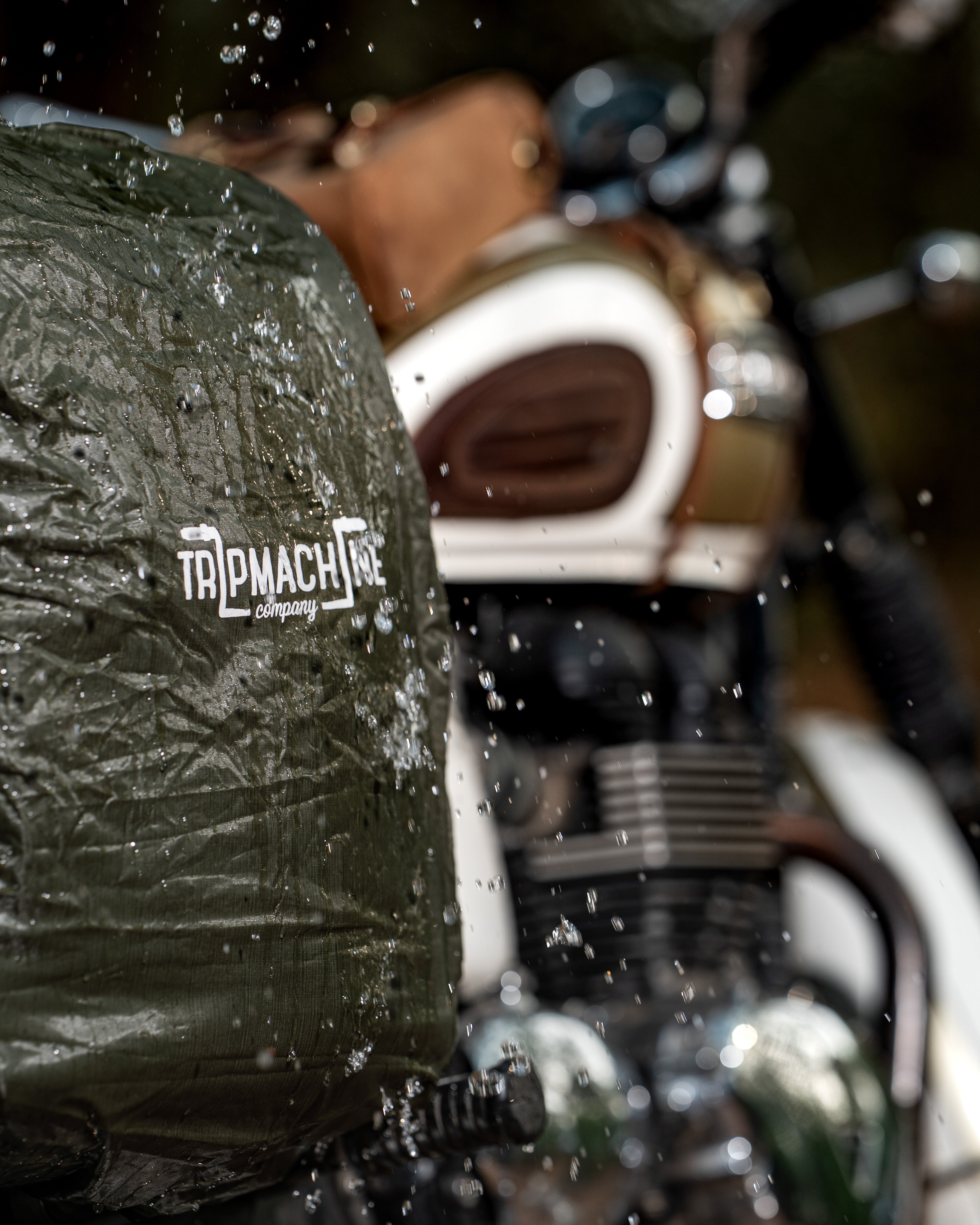 Motorcycle with a green cover featuring 'Top Mach' branding, surrounded by water droplets.
