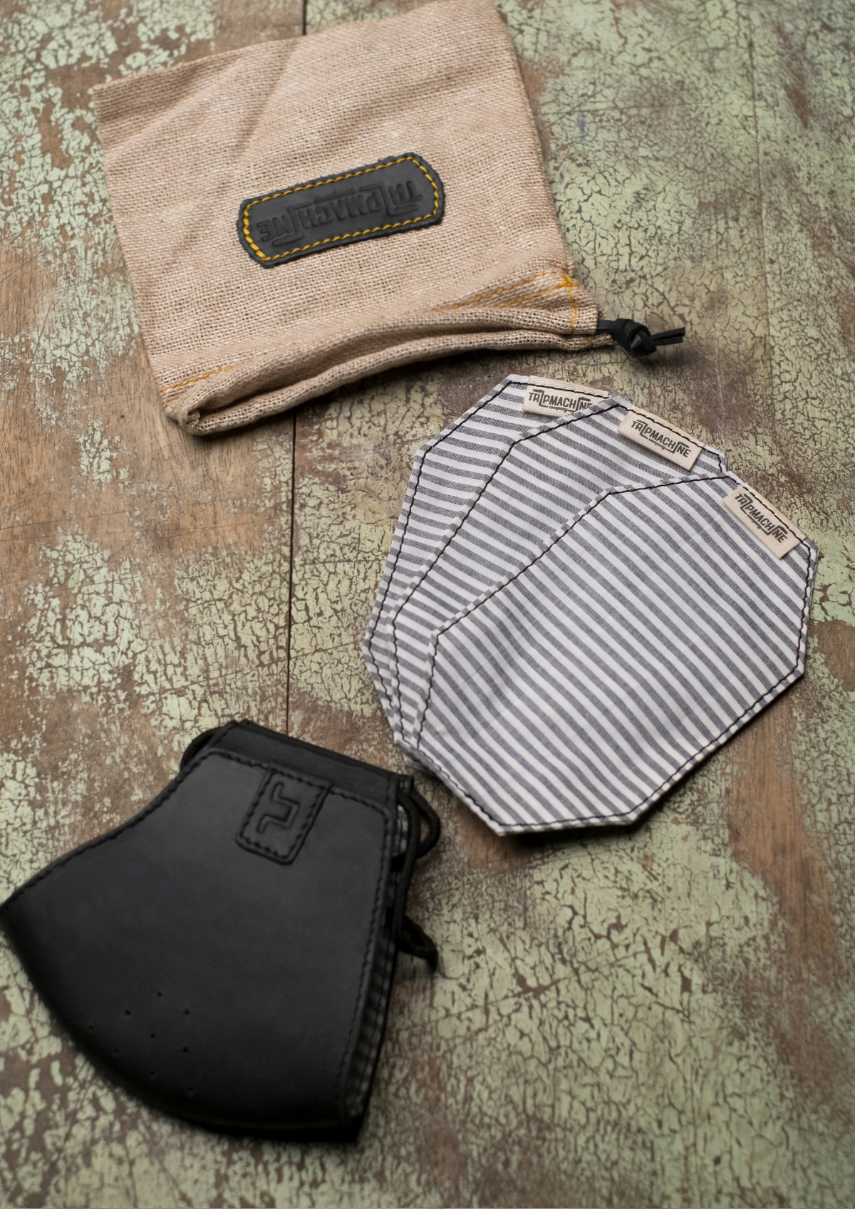 A black face mask with the pack of three striped face mask replacement filters and a carry bag