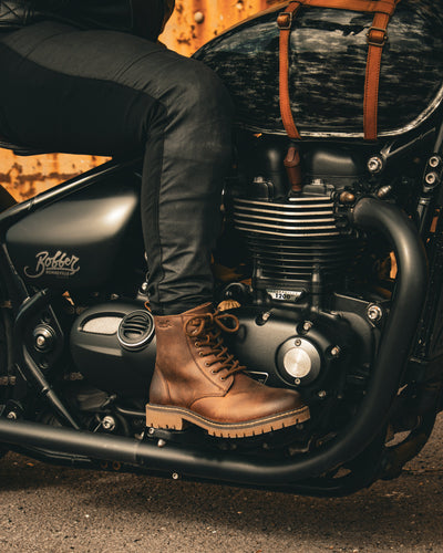 Person wearing brown boots on a motorcycle with a blurred background