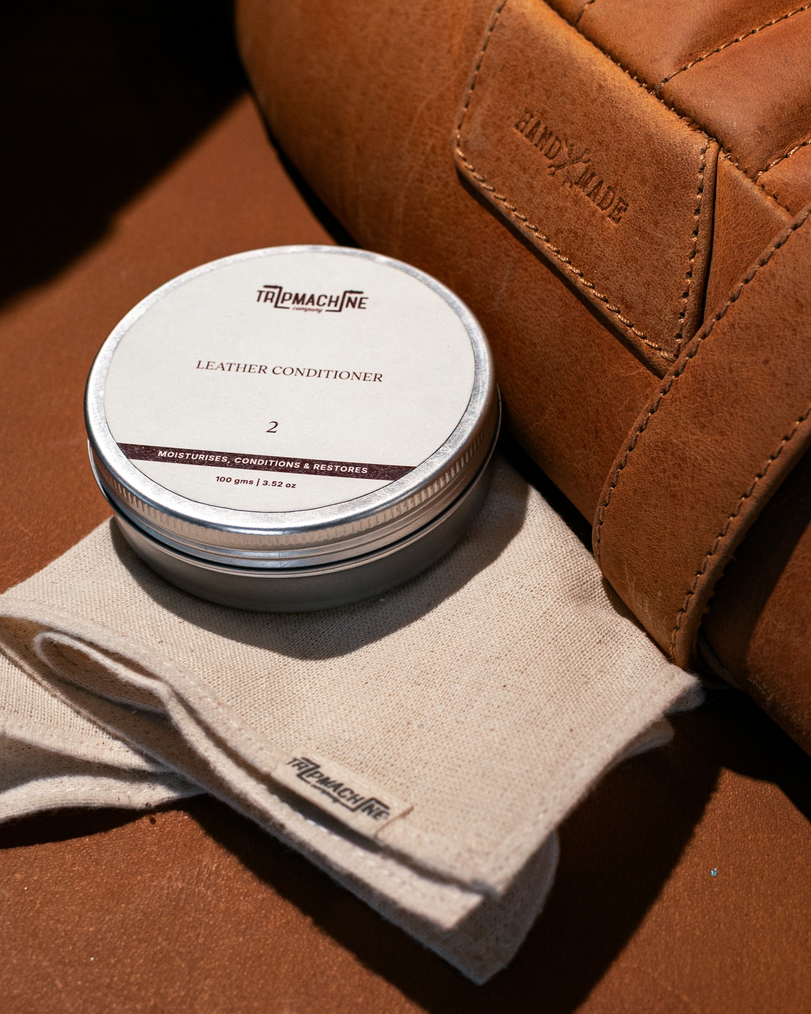 Leather conditioner tin with a cloth on a brown leather surface