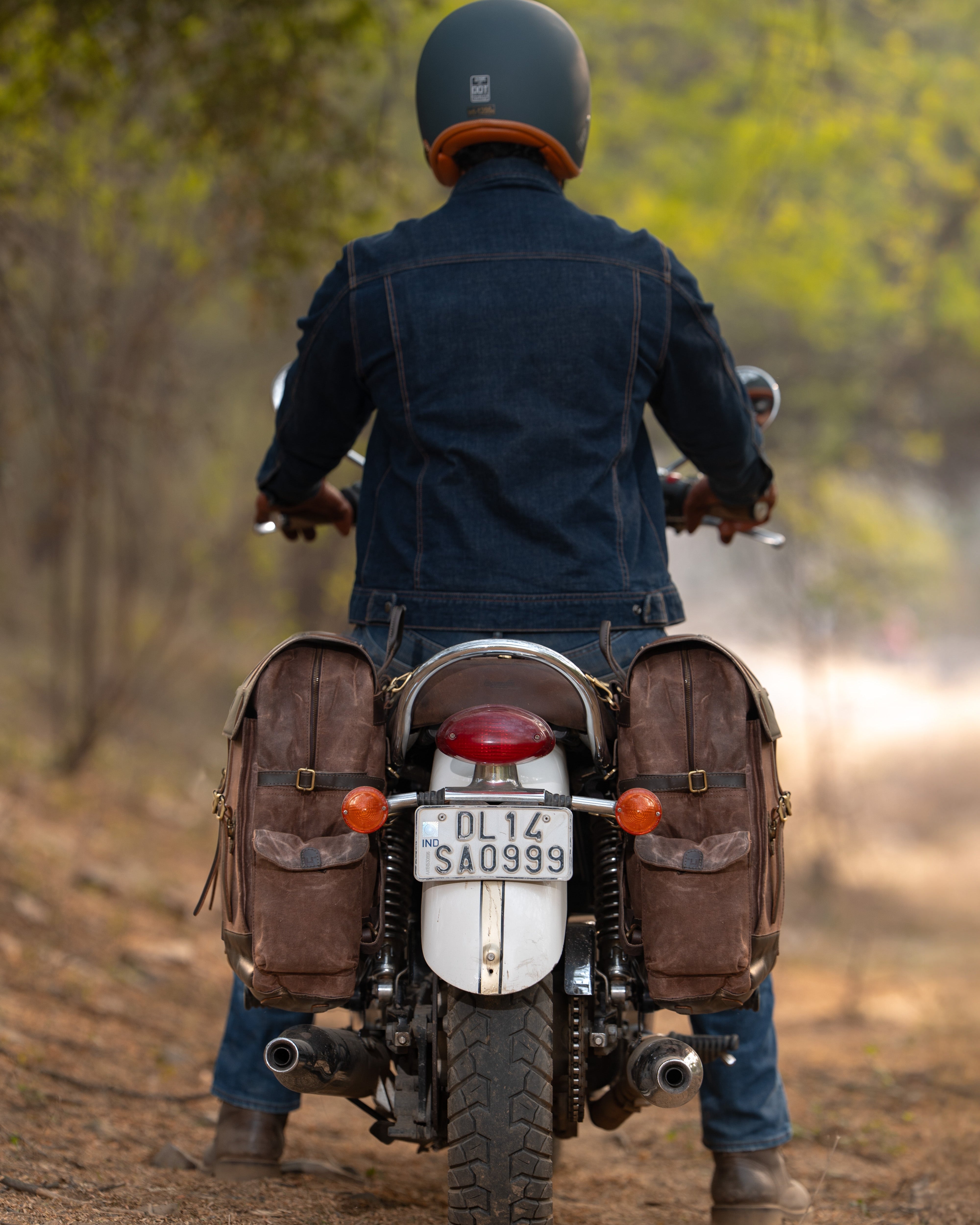 Person riding a motorcycle with saddlebags on a dirt road