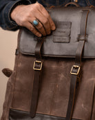 Person holding a leather backpack with visible branding