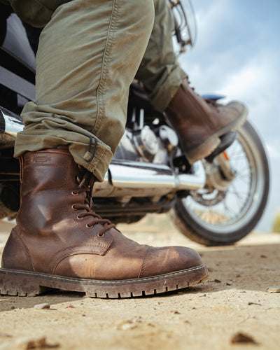 Brown leather boots on a motorcycle with a blurred background