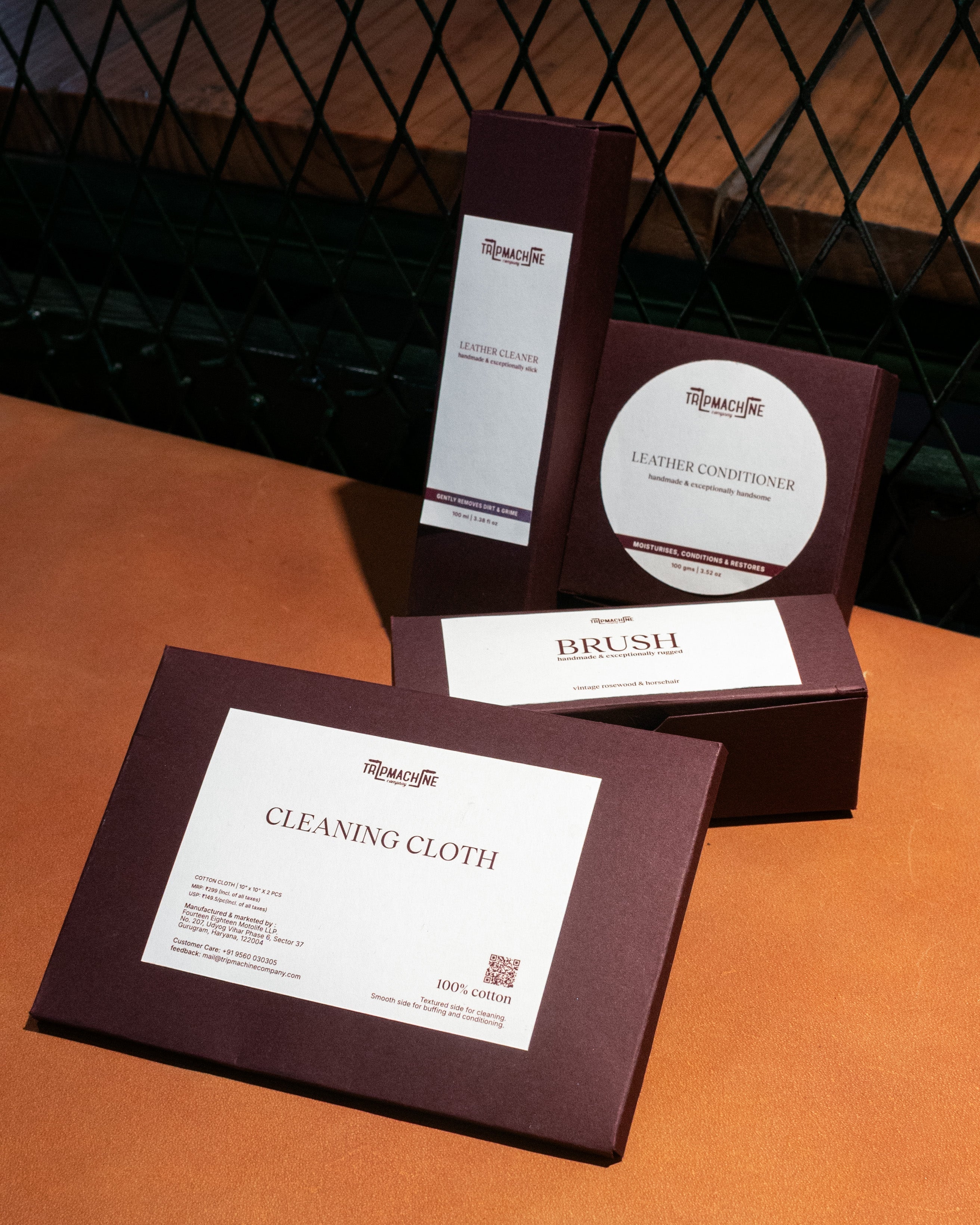 Set of leather care products including a cloth, brush, and conditioner on a brown surface.