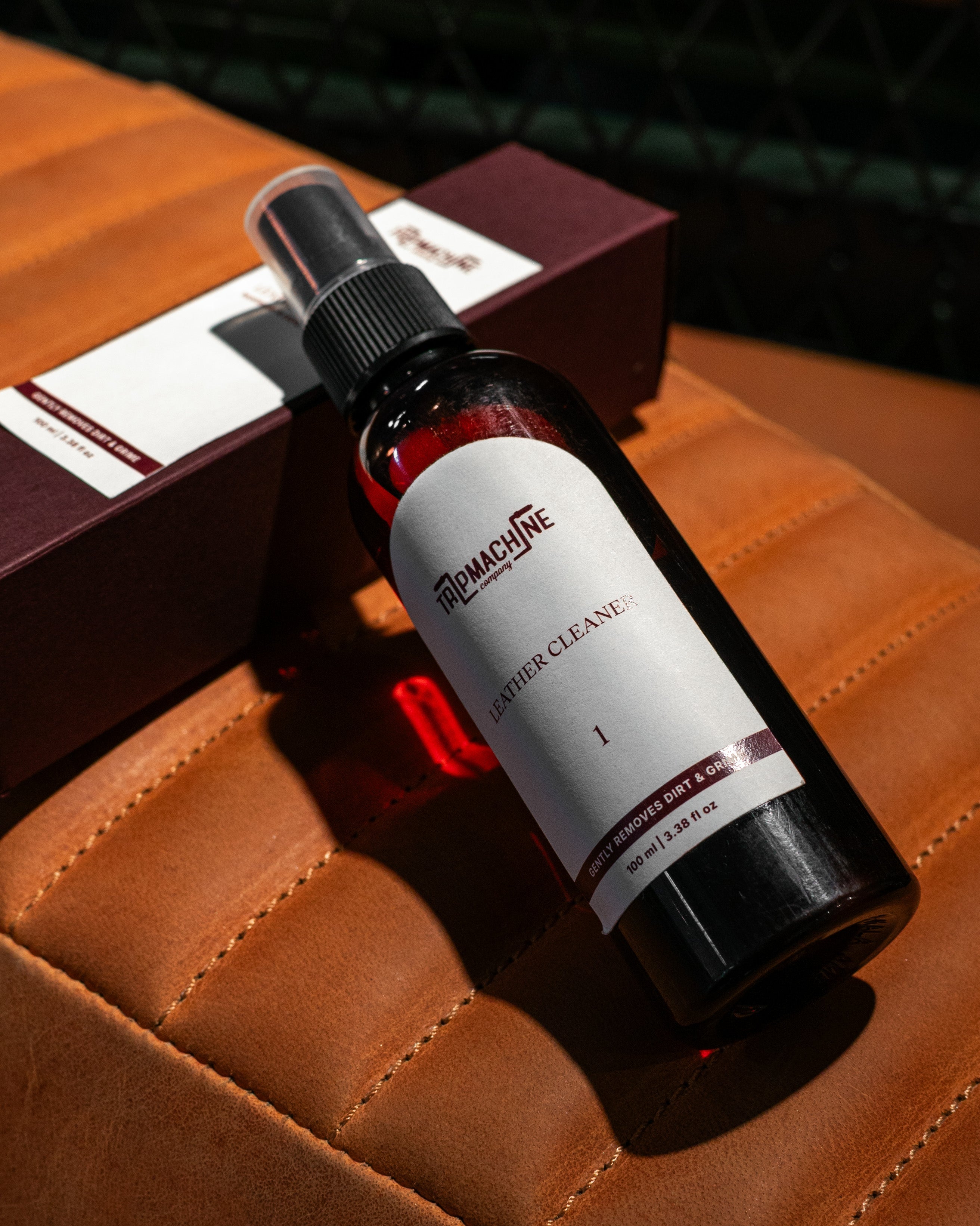 Bottle of Leather Cleaner on a brown leather surface with a box in the background.