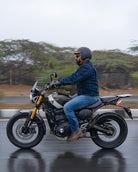 Person riding a motorcycle on a wet road with trees in the background