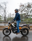 Person on a motorcycle on a wet road with trees in the background